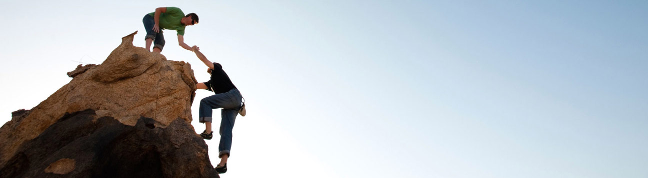 Rock climber assisting another climber onto a pinnacle